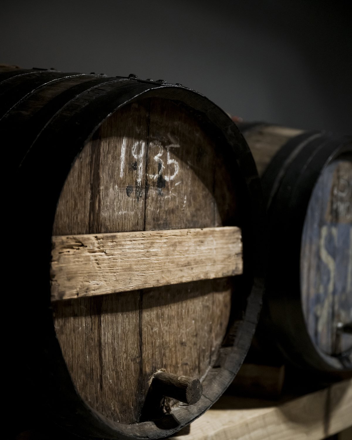 Barrica de roble marcada con el año 1935 en una nave de crianza en penumbra