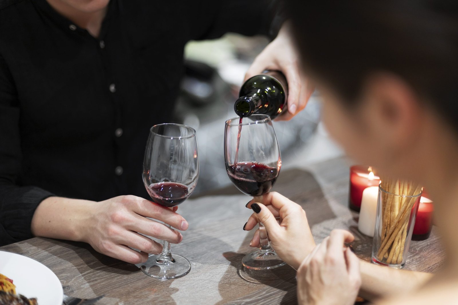 Brindis con copas de vino tinto en una cena íntima a la luz de las velas