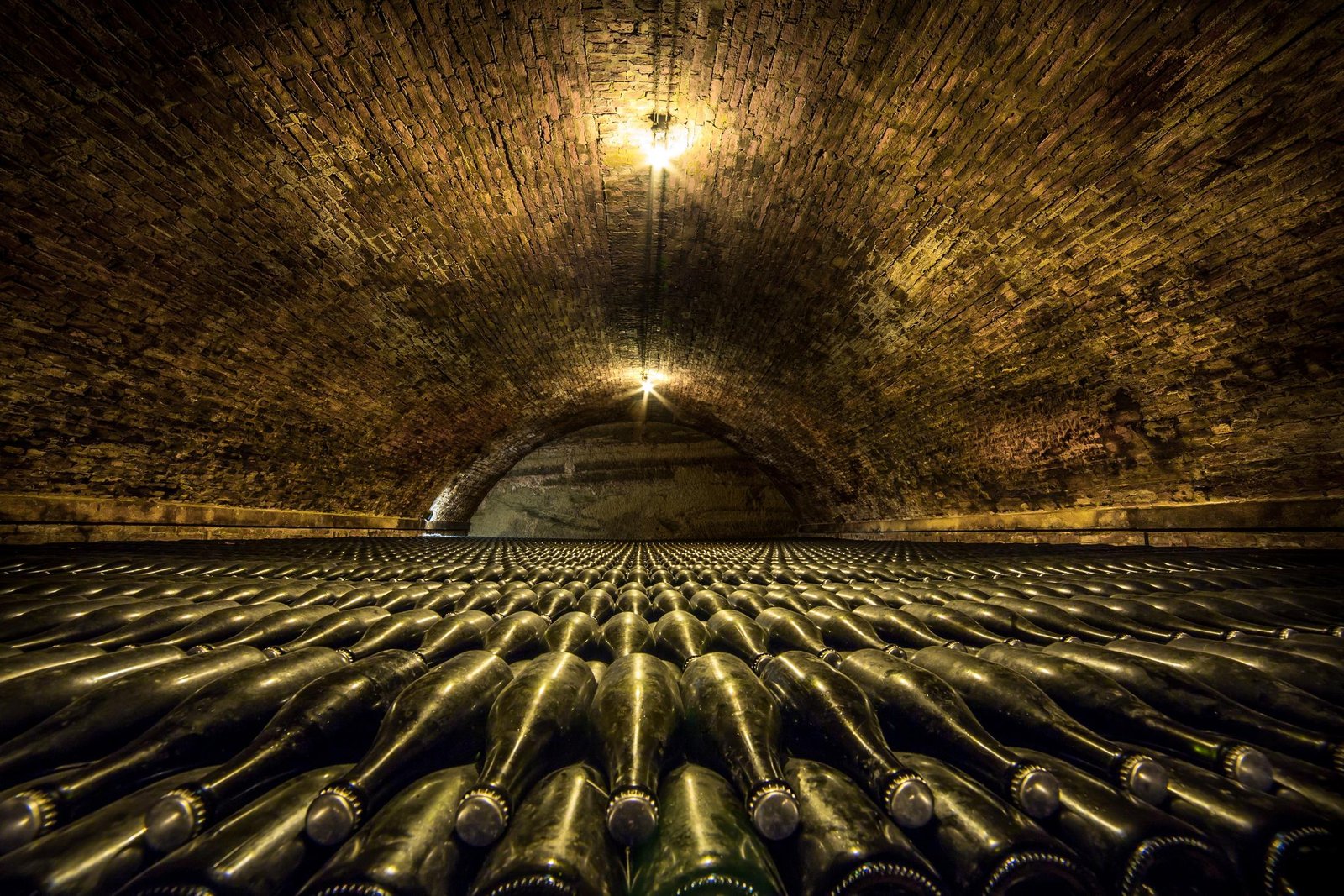 Túnel de una bodega histórica con botellas en crianza al fondo