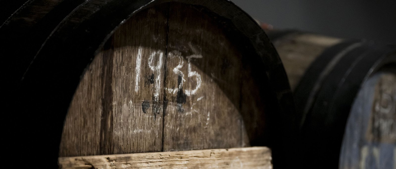 Barrica de roble antigua con la añada 1935 escrita a tiza en una bodega